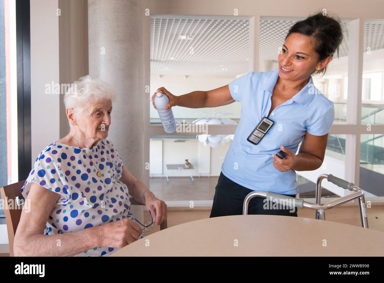 EHPAD - soignant malentendant pulvérisant de l'eau sur le visage d'un résident âgé pendant la forte chaleur estivale. Banque D'Images