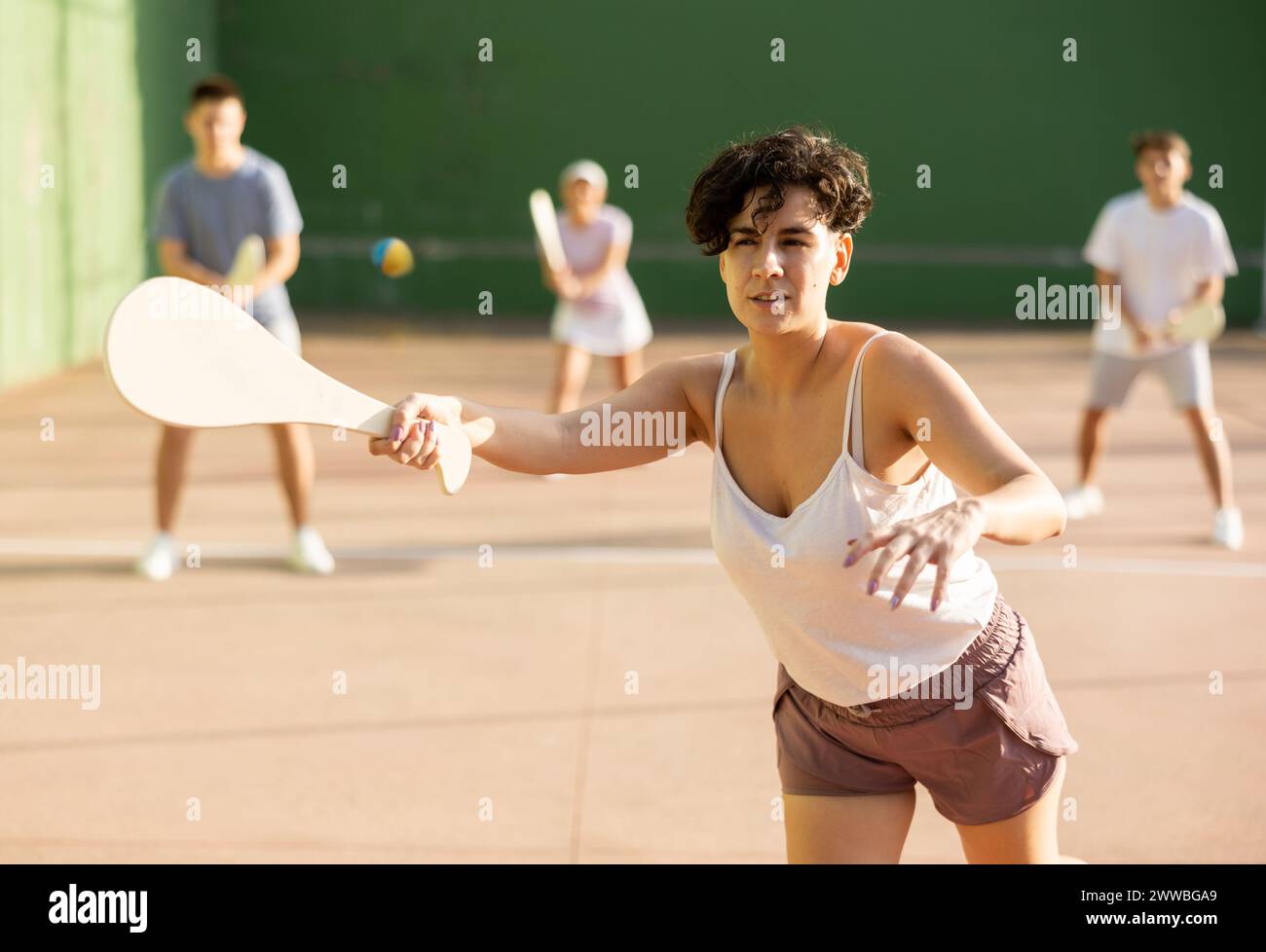 Femme servant le ballon pendant le jeu frontenis à l'extérieur Banque D'Images