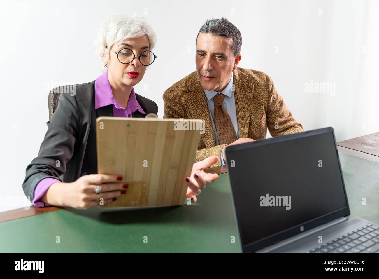 Deux personnes - examiner un contrat sur un presse-papiers avant de le finaliser - concentration intense sur les détails du document, vérification avant signature - consultation juridique Banque D'Images