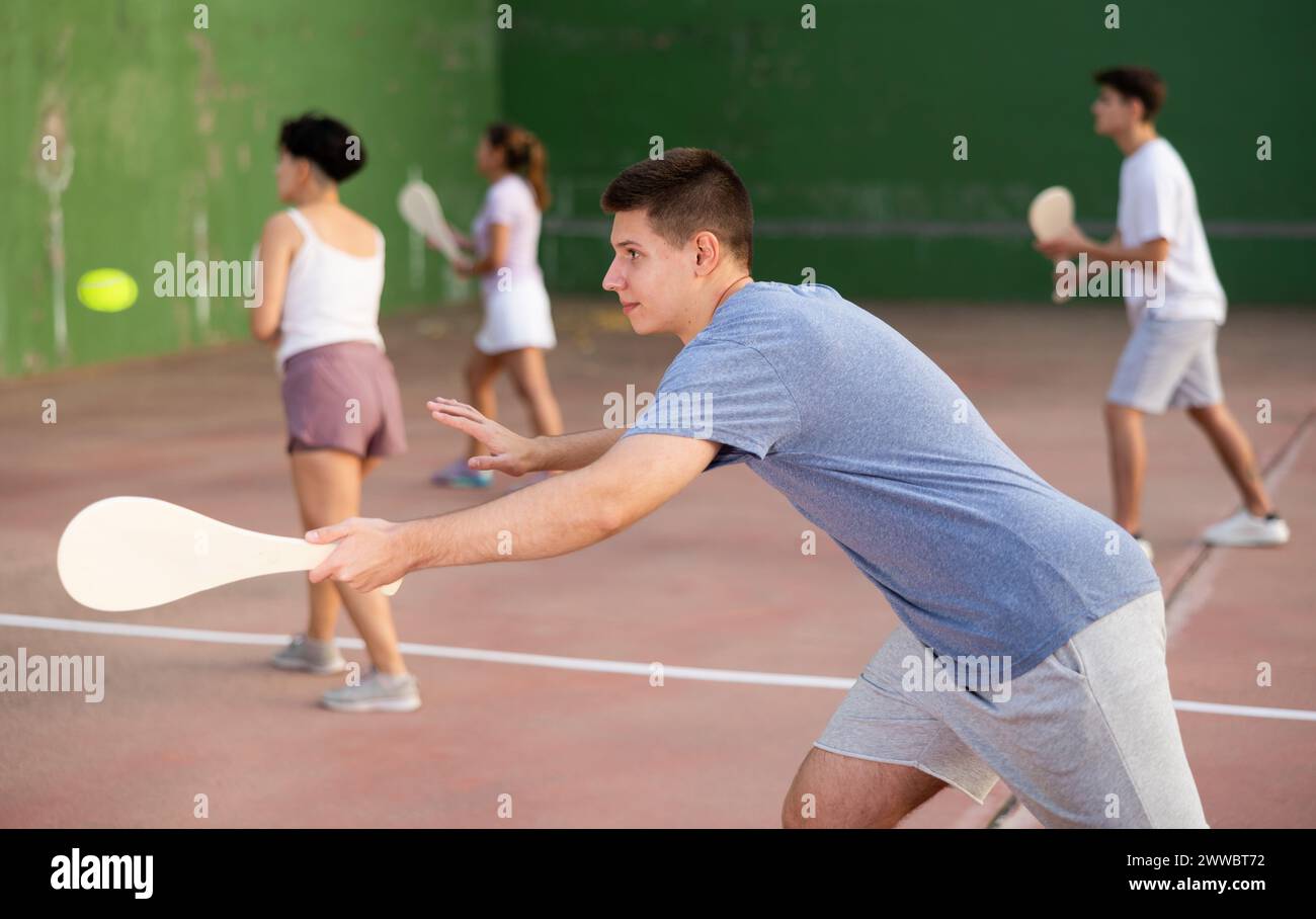 Jeune homme joueur de pelote frapper balle avec raquette Banque D'Images