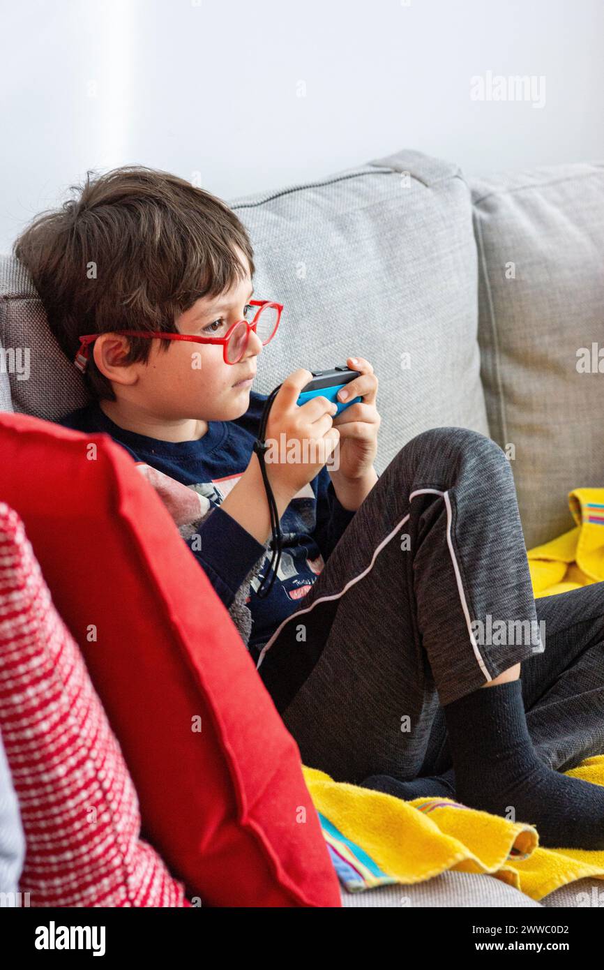 Garçon de 6 ans jouant avec une commande bleue de la Nintendo Switch Banque D'Images