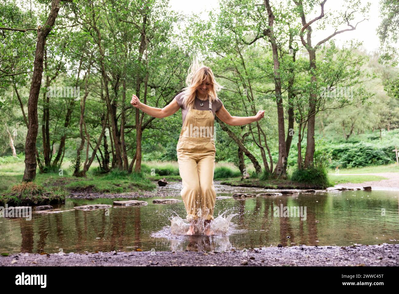 Femme joyeuse sautant dans la rivière Banque D'Images