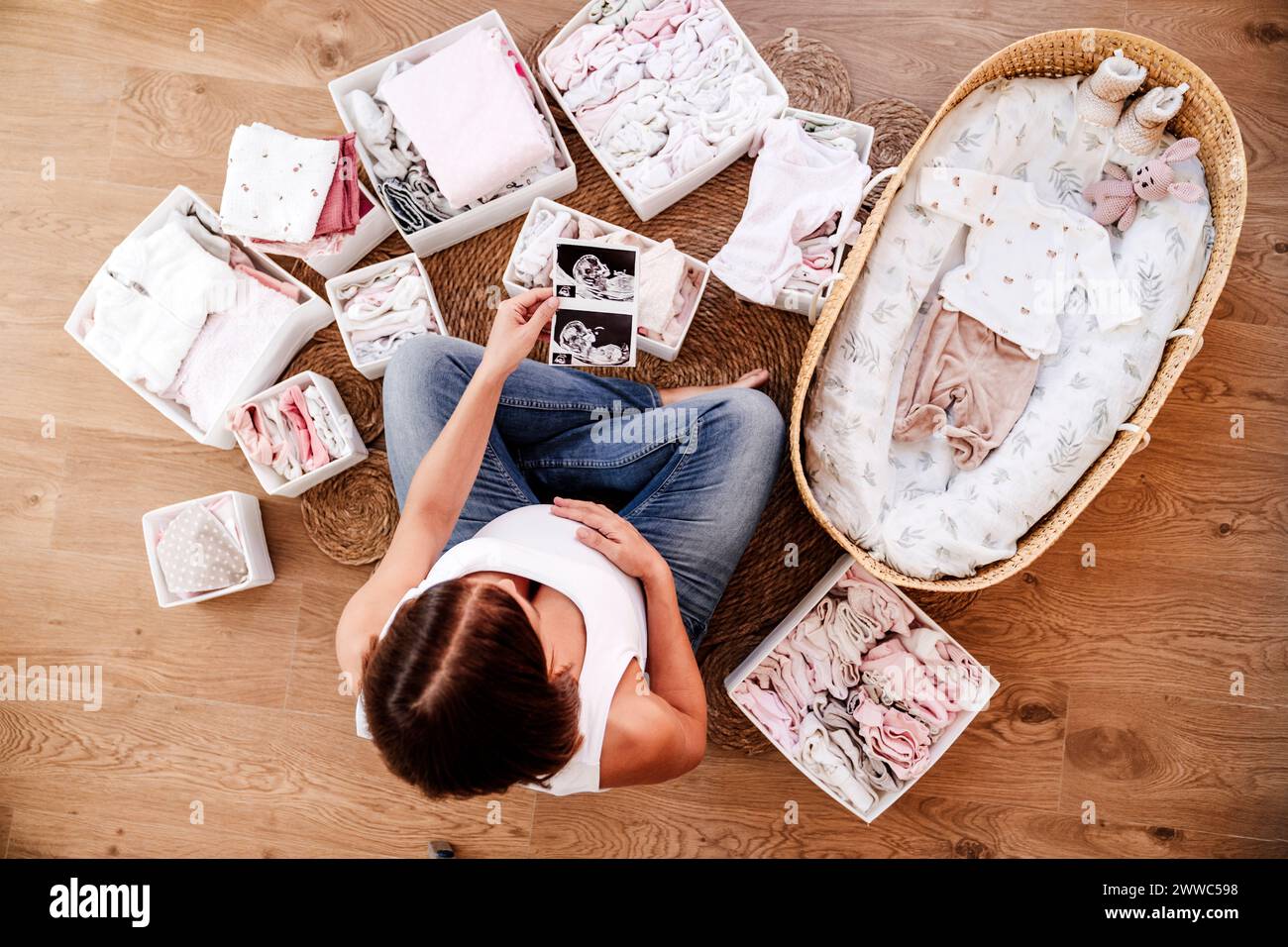 Femme enceinte tenant des photographies échographiques près du panier de moses à la maison Banque D'Images