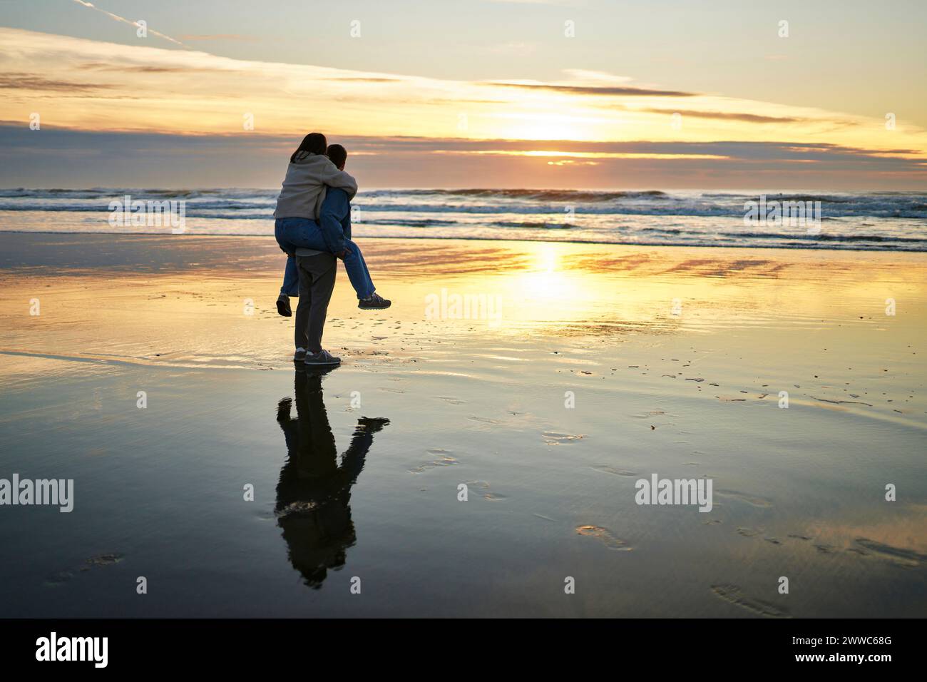 Jeune homme piggyback petite amie et marchant près de la mer sur la plage Banque D'Images