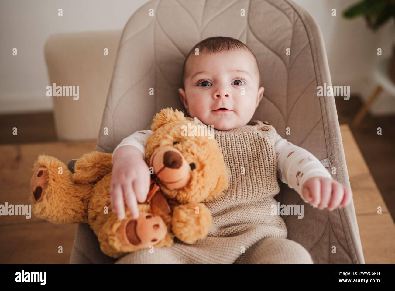 Jolie petite fille assise avec jouet en peluche sur la chaise de videur Banque D'Images
