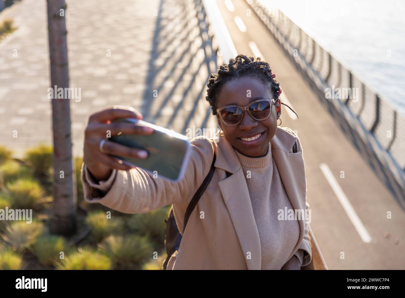 Femme souriante prenant le selfie par téléphone portable Banque D'Images