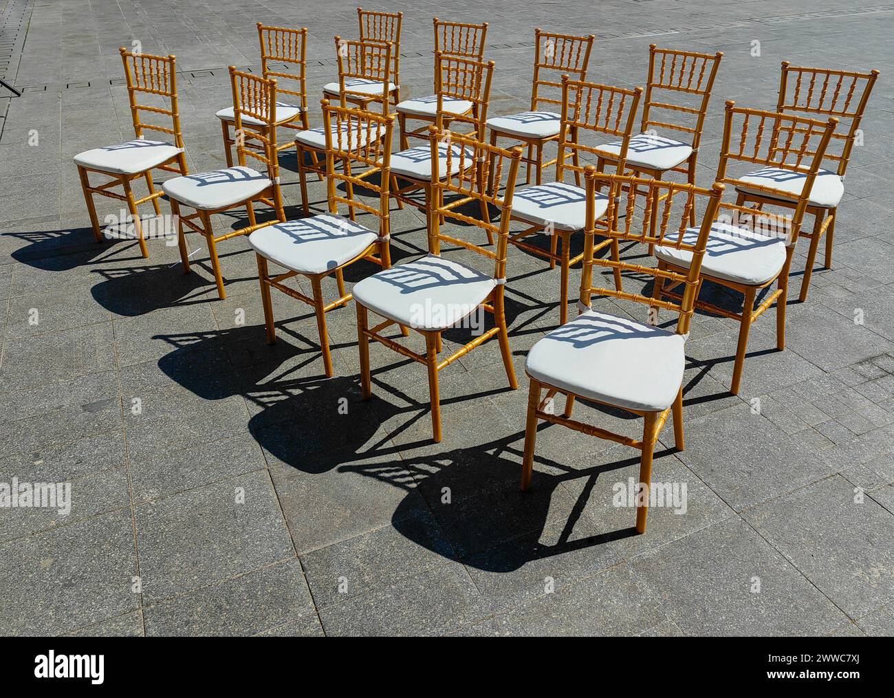 Sièges ensoleillés. Un défilé de 15 chaises sur la place de la ville. Lumière et ombre. Motif et texture. Banque D'Images