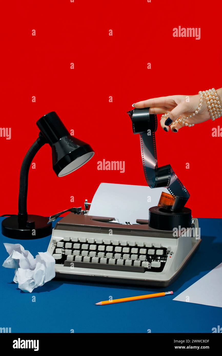 Main de l'écrivain tenant le négatif de film près de la machine à écrire sur le bureau Banque D'Images