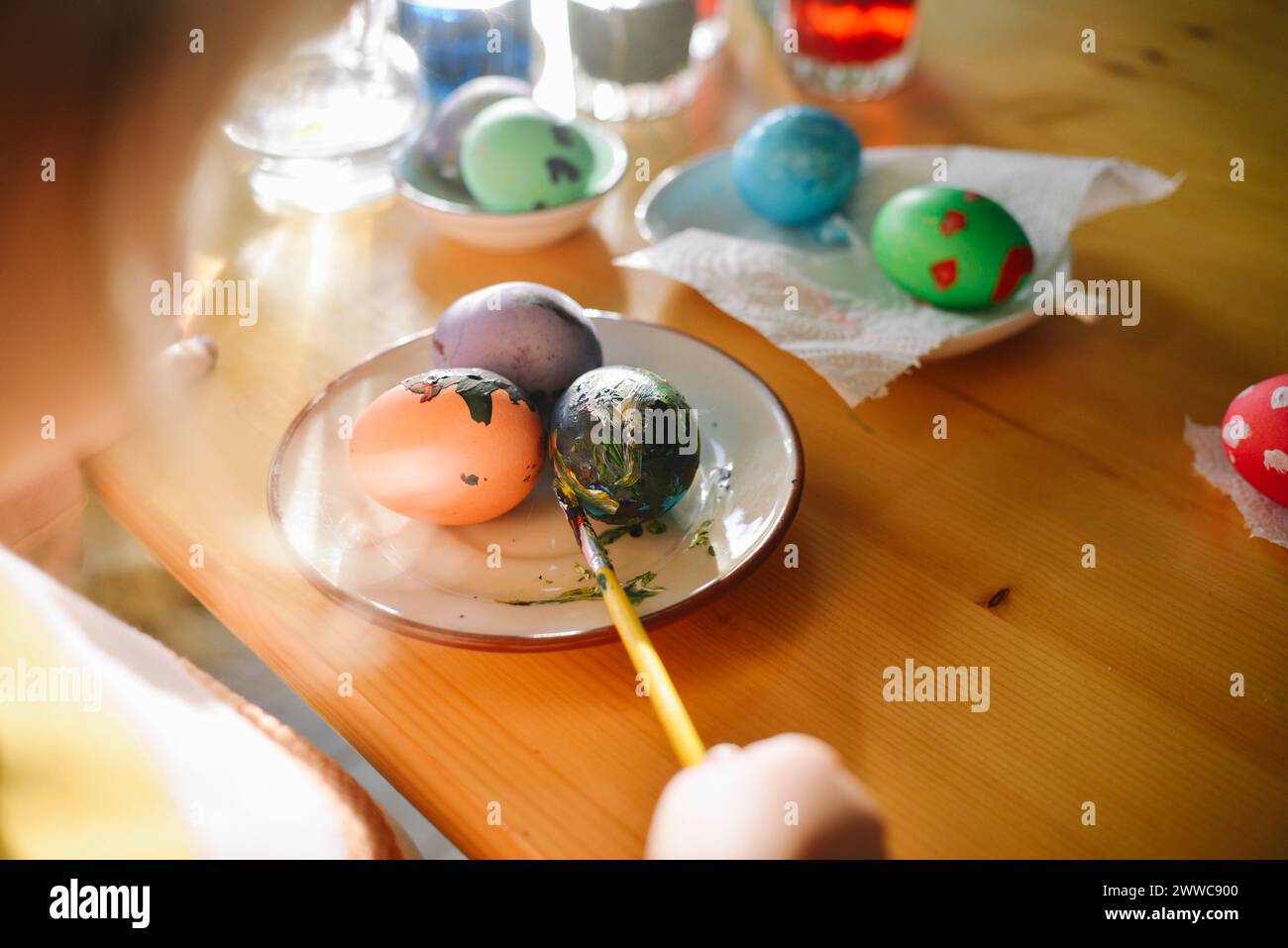 Fille coloriant les oeufs de Pâques dans l'assiette à la maison Banque D'Images