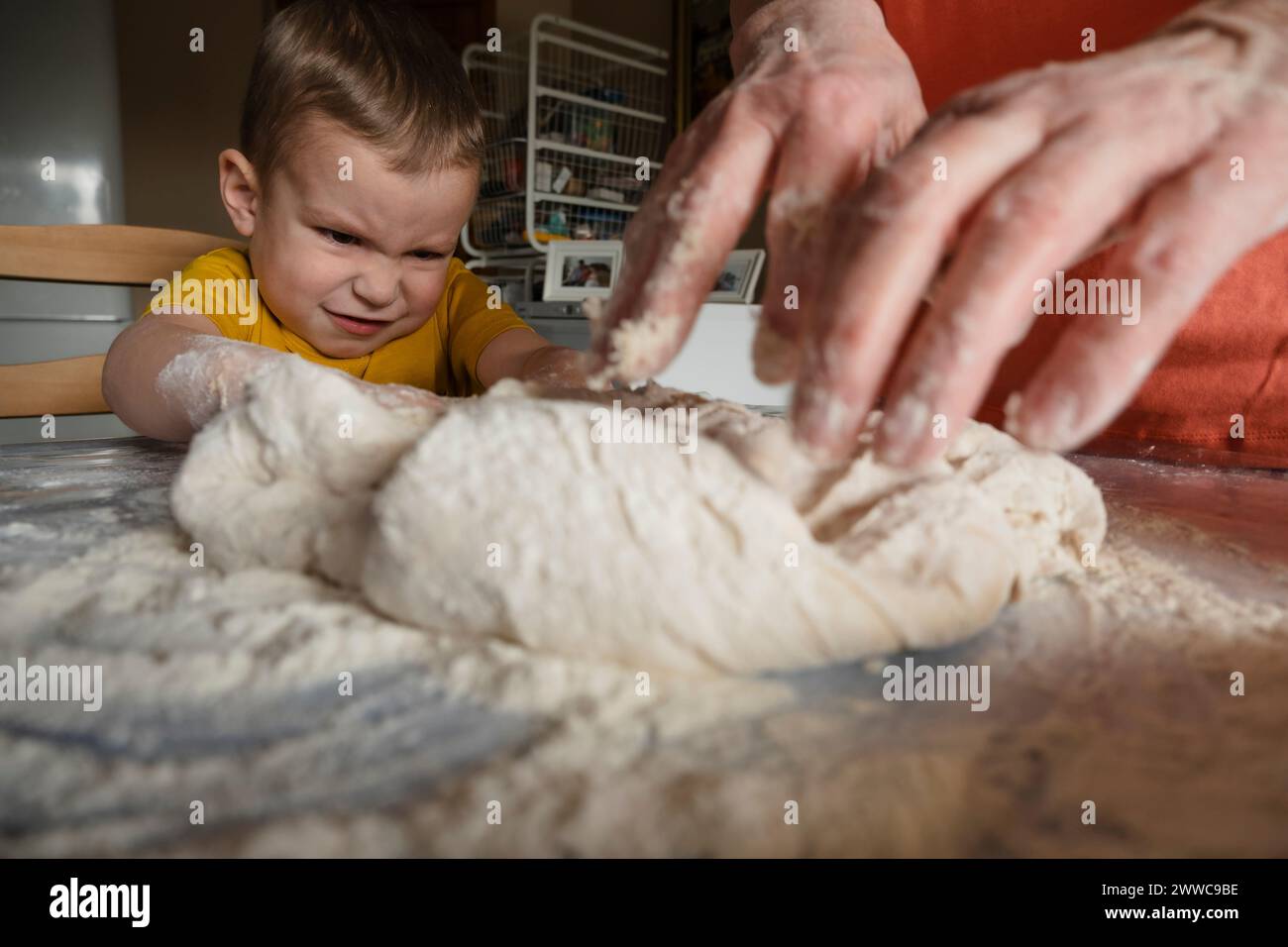 Garçon pétrissant la pâte avec grand-mère dans la cuisine à la maison Banque D'Images