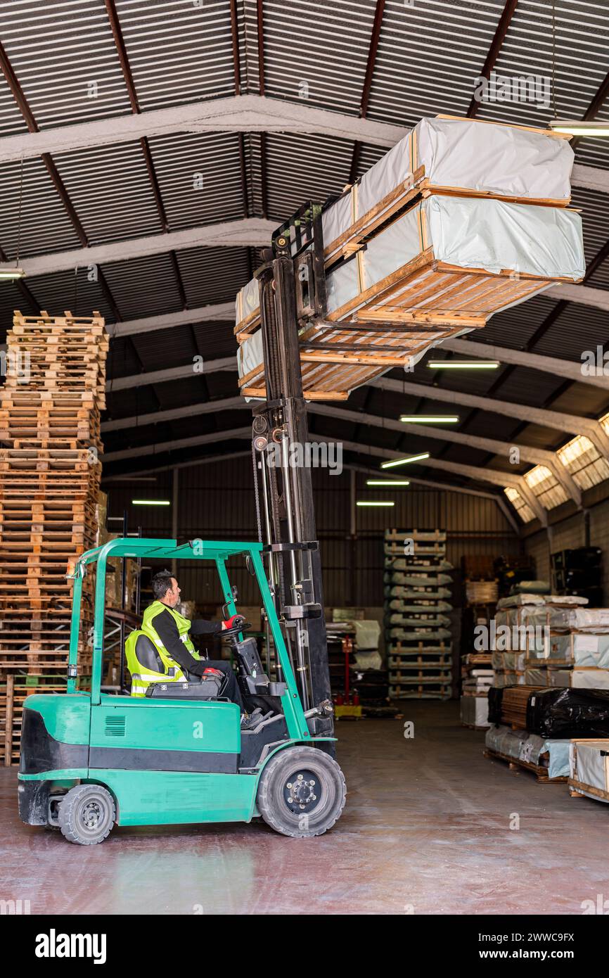 Ouvrier de chariot élévateur transportant des palettes en bois à l'entrepôt Banque D'Images