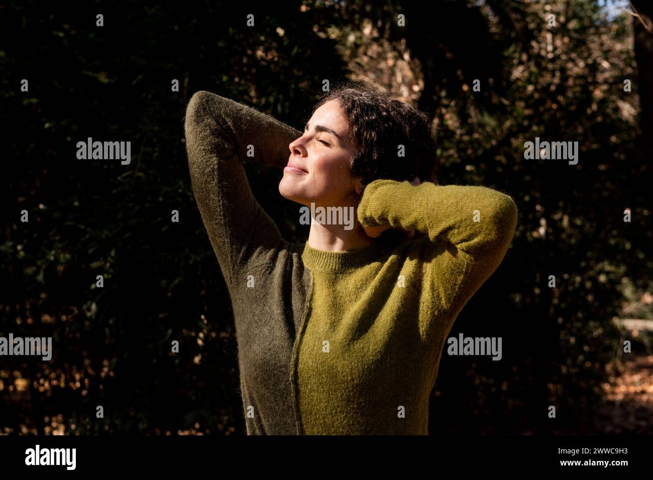 Femme souriante debout avec les mains derrière la tête au parc Banque D'Images