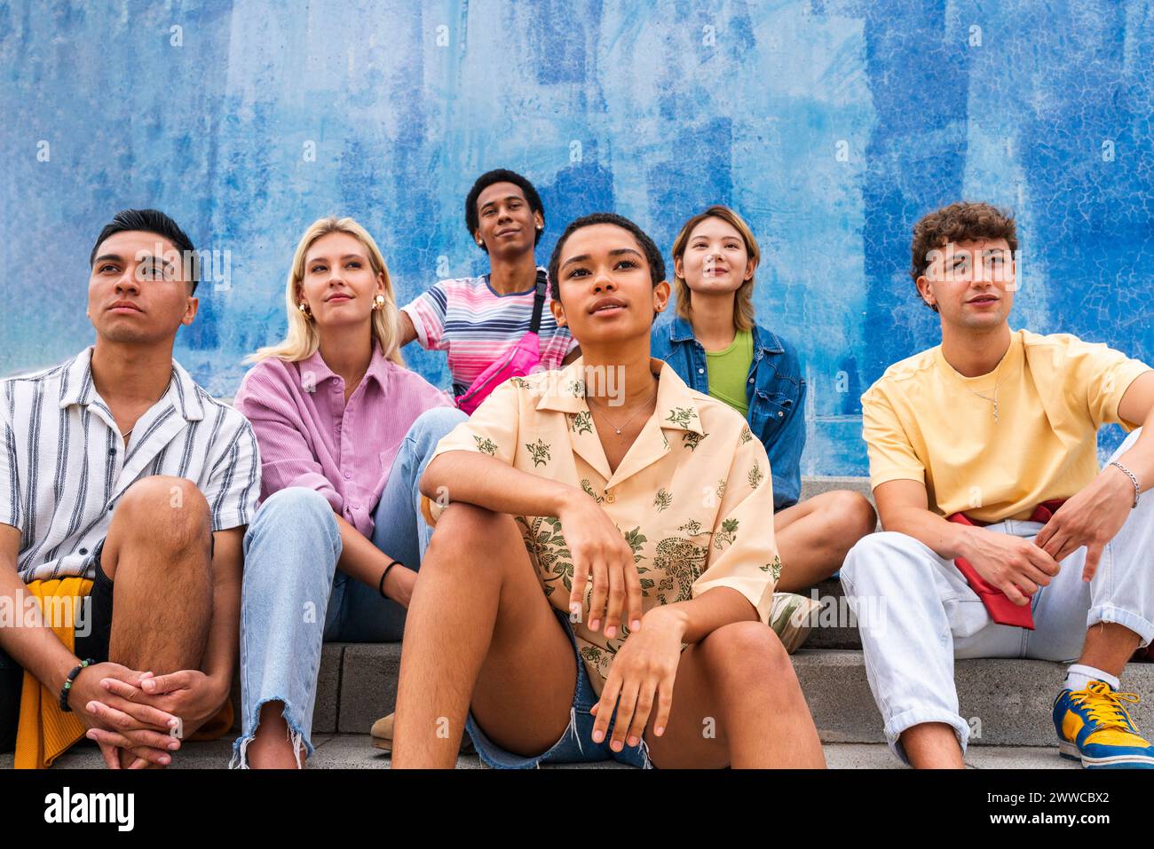 Jeunes confiants assis sur des marches devant le mur Banque D'Images