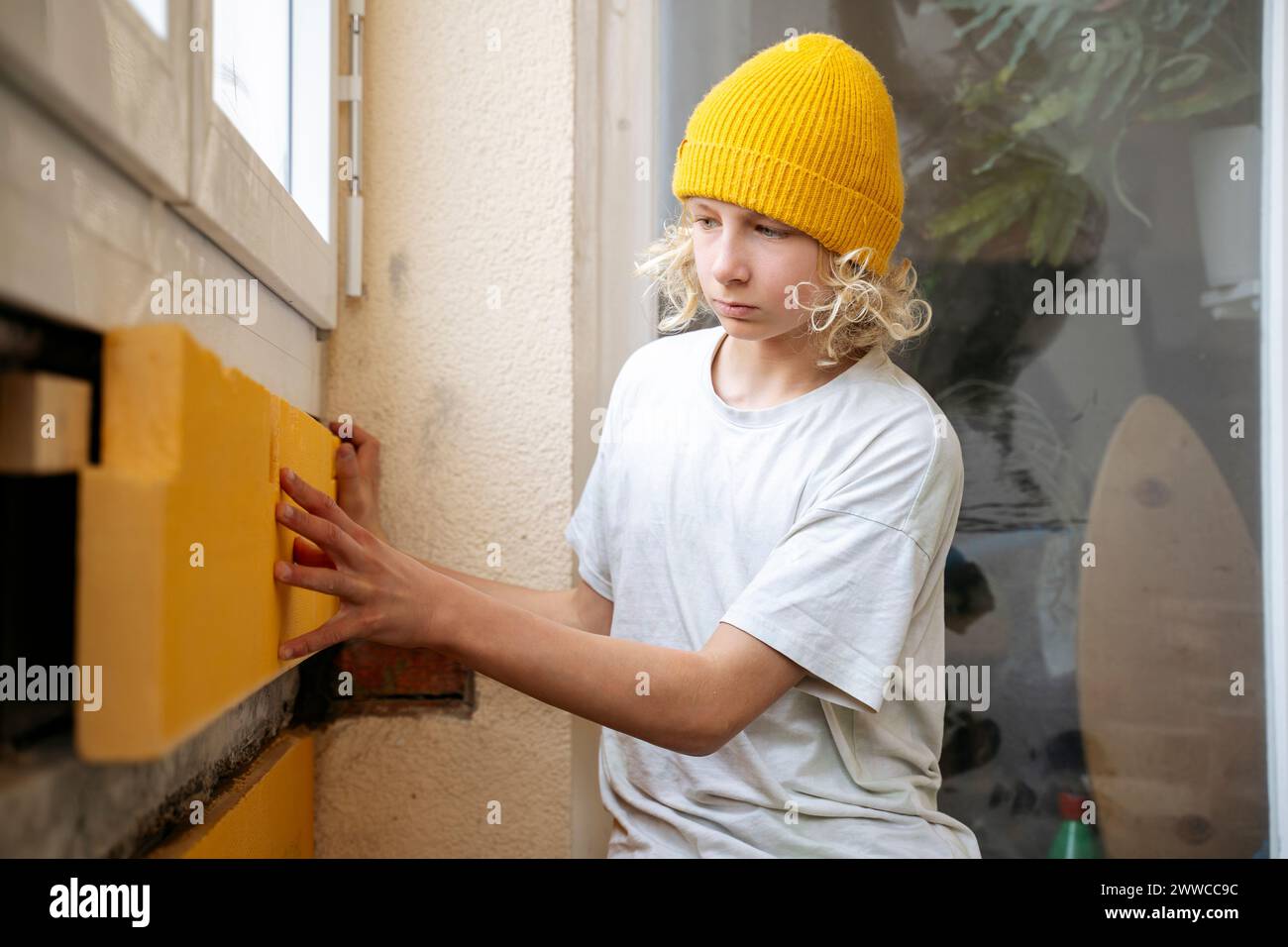 Garçon installant l'isolation sur le mur dans la chambre en rénovation Banque D'Images