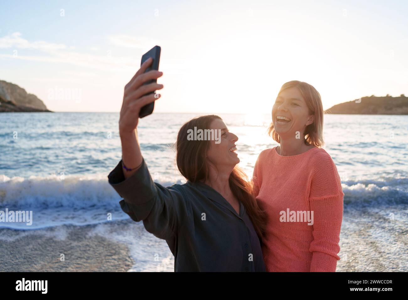 Amis joyeux prenant selfie ensemble sur le rivage à la plage Banque D'Images