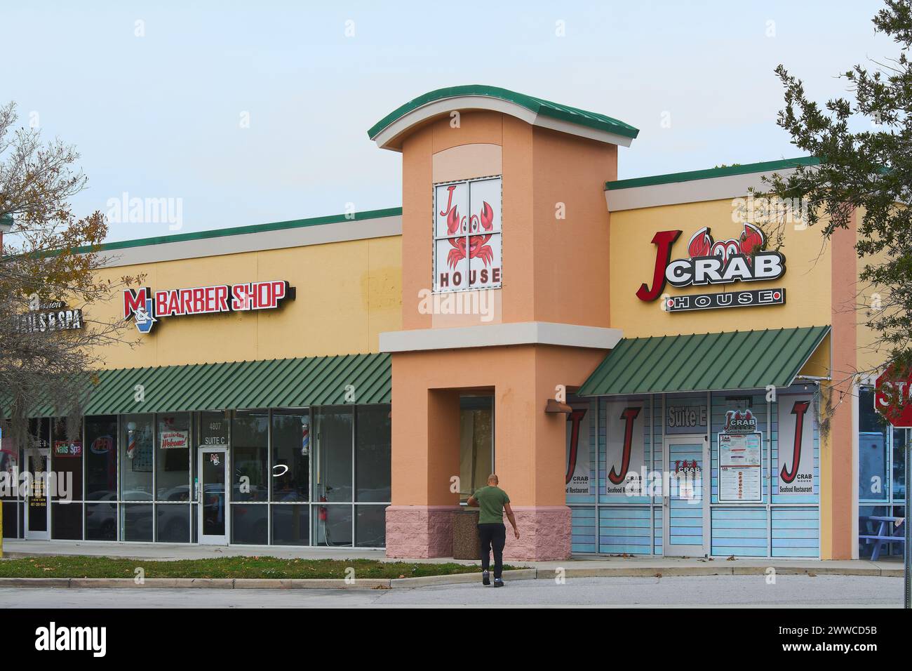 Floride, États-Unis - 23 mars 2024 une personne se promène dans un centre commercial où se distinguent un salon de coiffure et un restaurant de fruits de mer, montrant la variété Banque D'Images