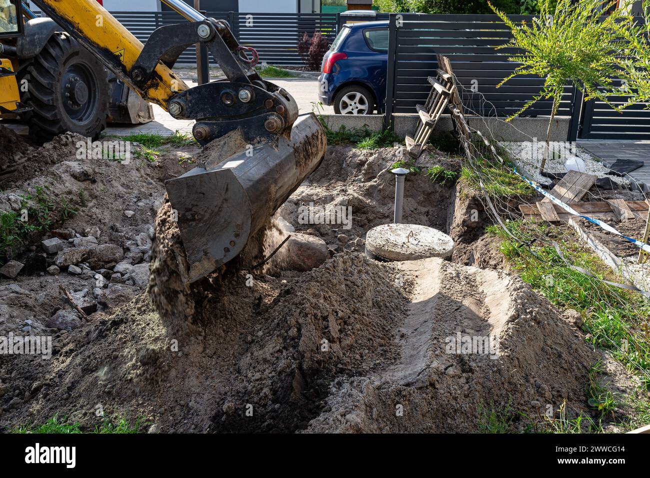 Utilisation d'une excavatrice pour enterrer une fosse septique en béton de 10 m3 située dans le jardin à côté de la maison. Banque D'Images