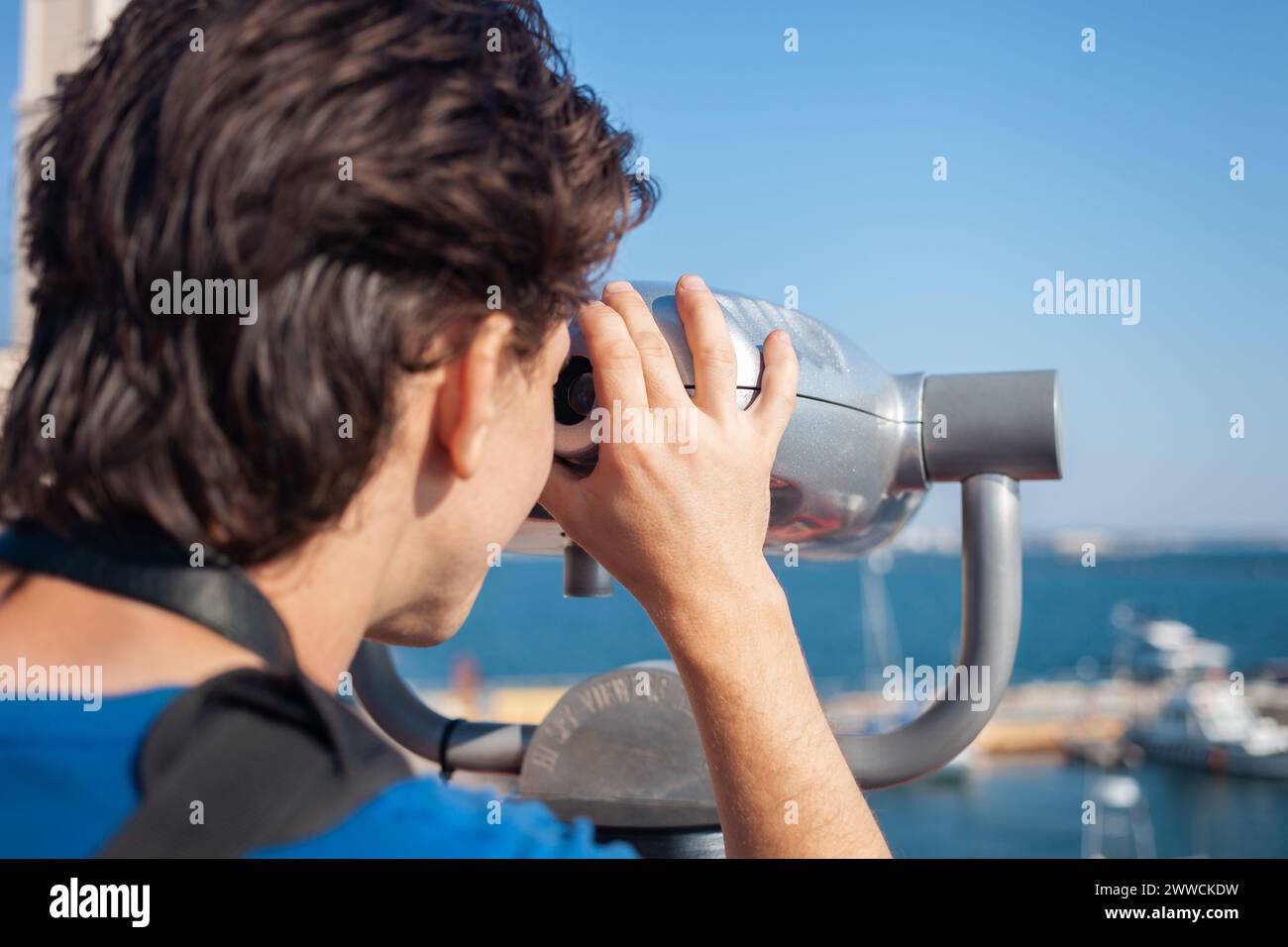 l'homme regarde à travers des jumelles stationnaires. Binoscope sur le pont d'observation près de la mer. port maritime à Odessa. Yachts chers sur la jetée. Machi commercial Banque D'Images