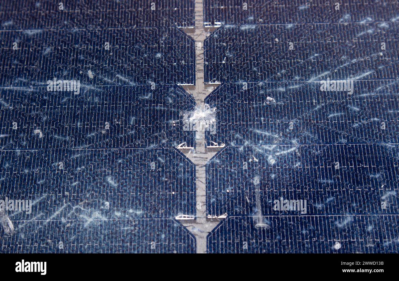 Vue rapprochée de la cellule en verre trempé du panneau solaire cassé endommagée. Bosselure de pierre au milieu avec des fissures de toile d'araignée autour. Banque D'Images