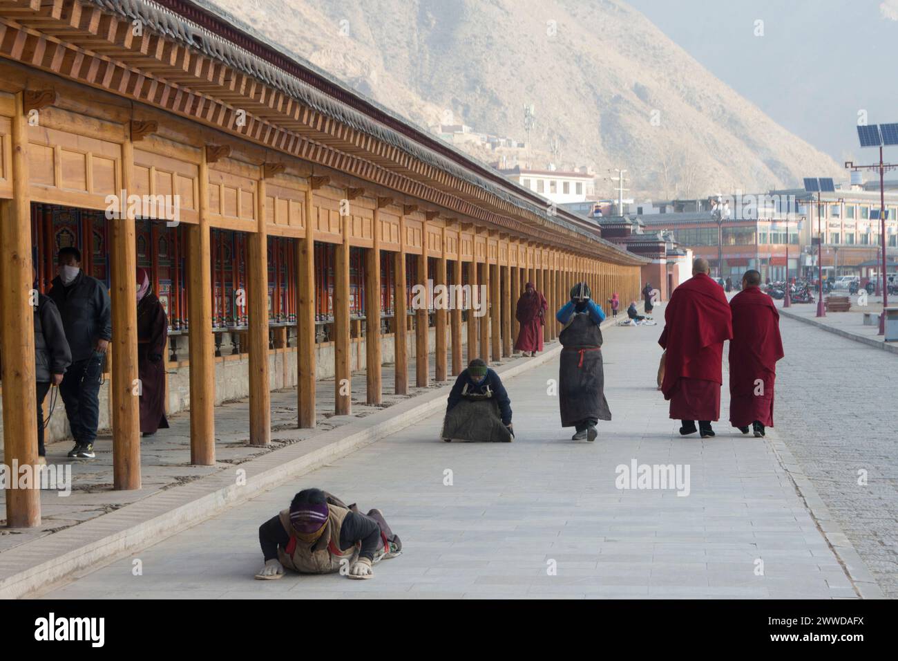 Pèlerins se prosternant le long des roues de prière autour du monastère de Labrang. Comté de Xiahe, préfecture autonome tibétaine du Gannan, Gansu, Chine Banque D'Images