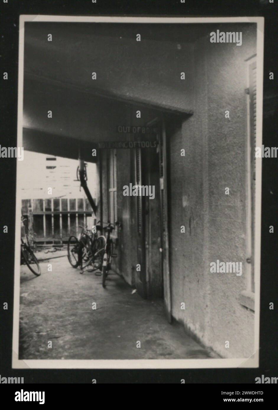 Vue de l'entrée de l'atelier de véhicules de police au Belize, 1950-1959, montrant les portes de garage, les véhicules de police et les bâtiments environnants. Banque D'Images