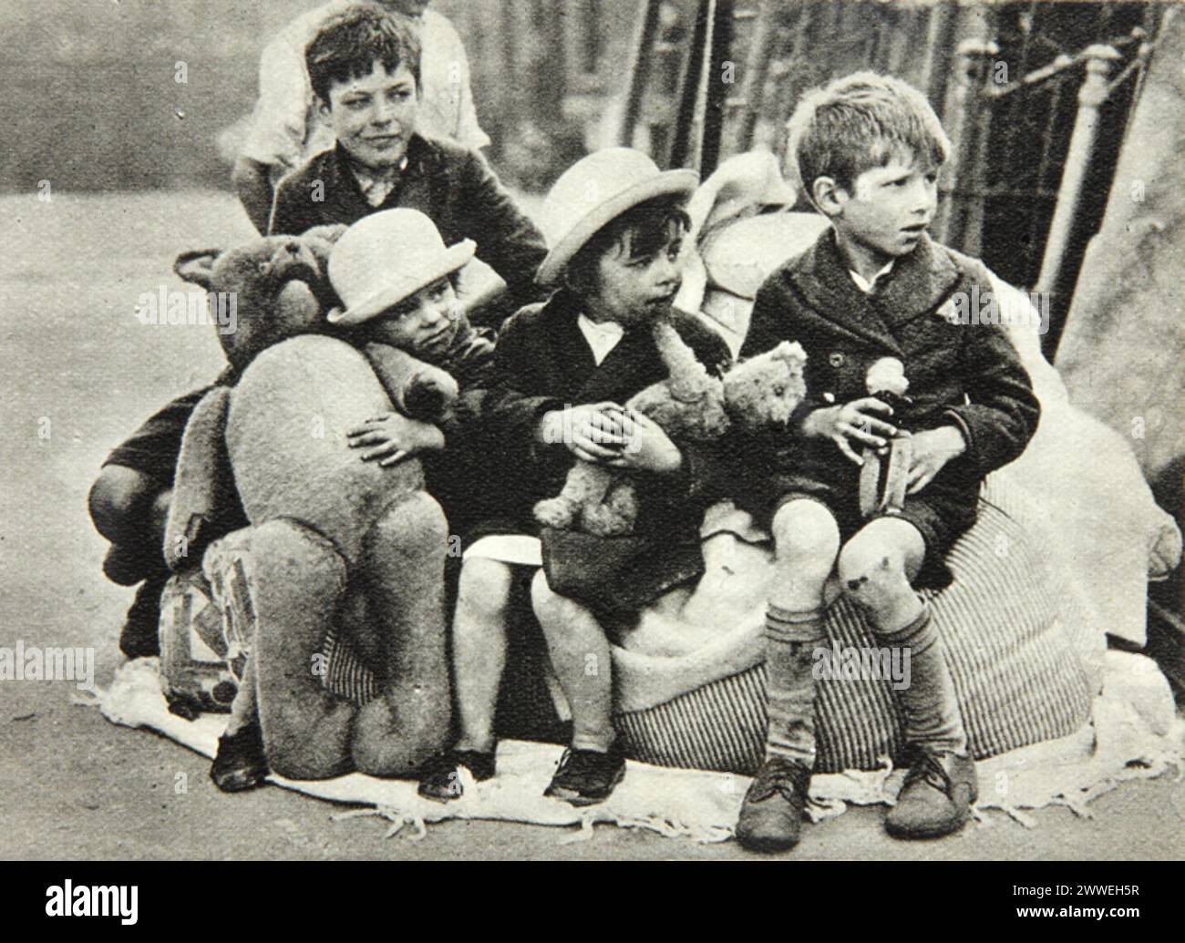 Photographie de 1941 montrant des enfants assis dans une rue endommagée par la bombe pendant le Blitz, produite par le ministère britannique de l'information pendant la seconde Guerre mondiale. Banque D'Images