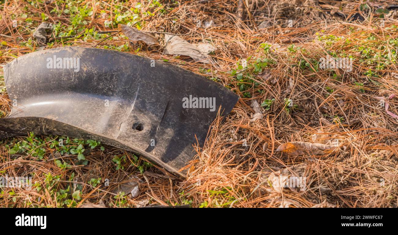 Une pièce de voiture en plastique fragile est abandonnée à l’extérieur sur l’herbe, contribuant à la pollution, en Corée du Sud Banque D'Images