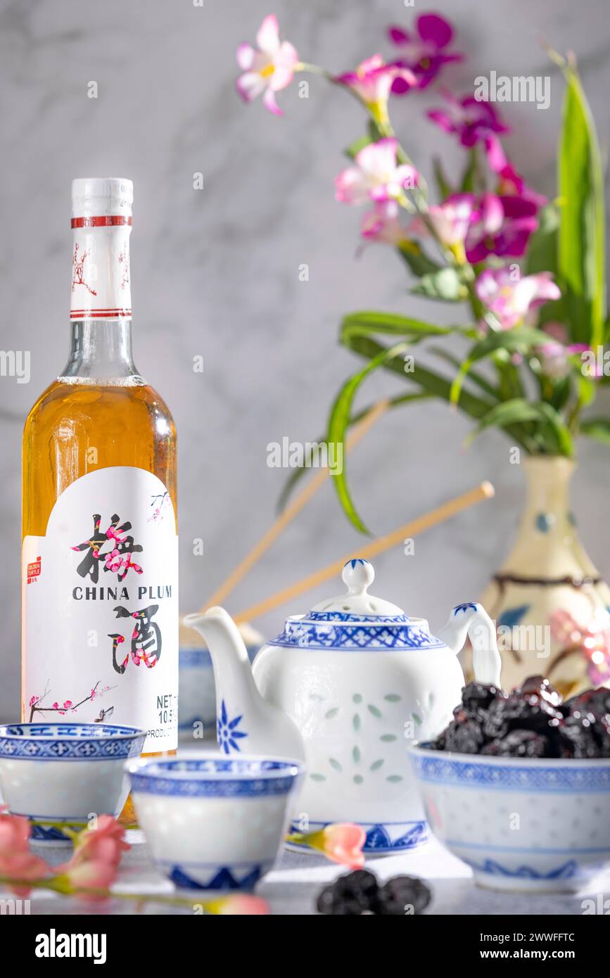 Service à thé asiatique aux motifs bleus, une bouteille de vin de prune chinois et des fruits secs Banque D'Images