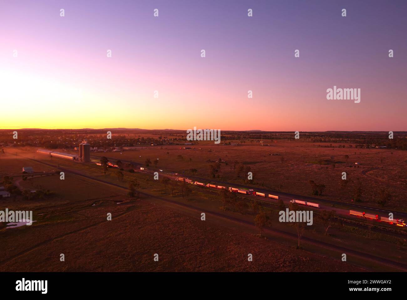 Aérien du coucher du soleil au-dessus de camions livrant du grain de blé au silo de Wallumbilla Queensland Australie Banque D'Images