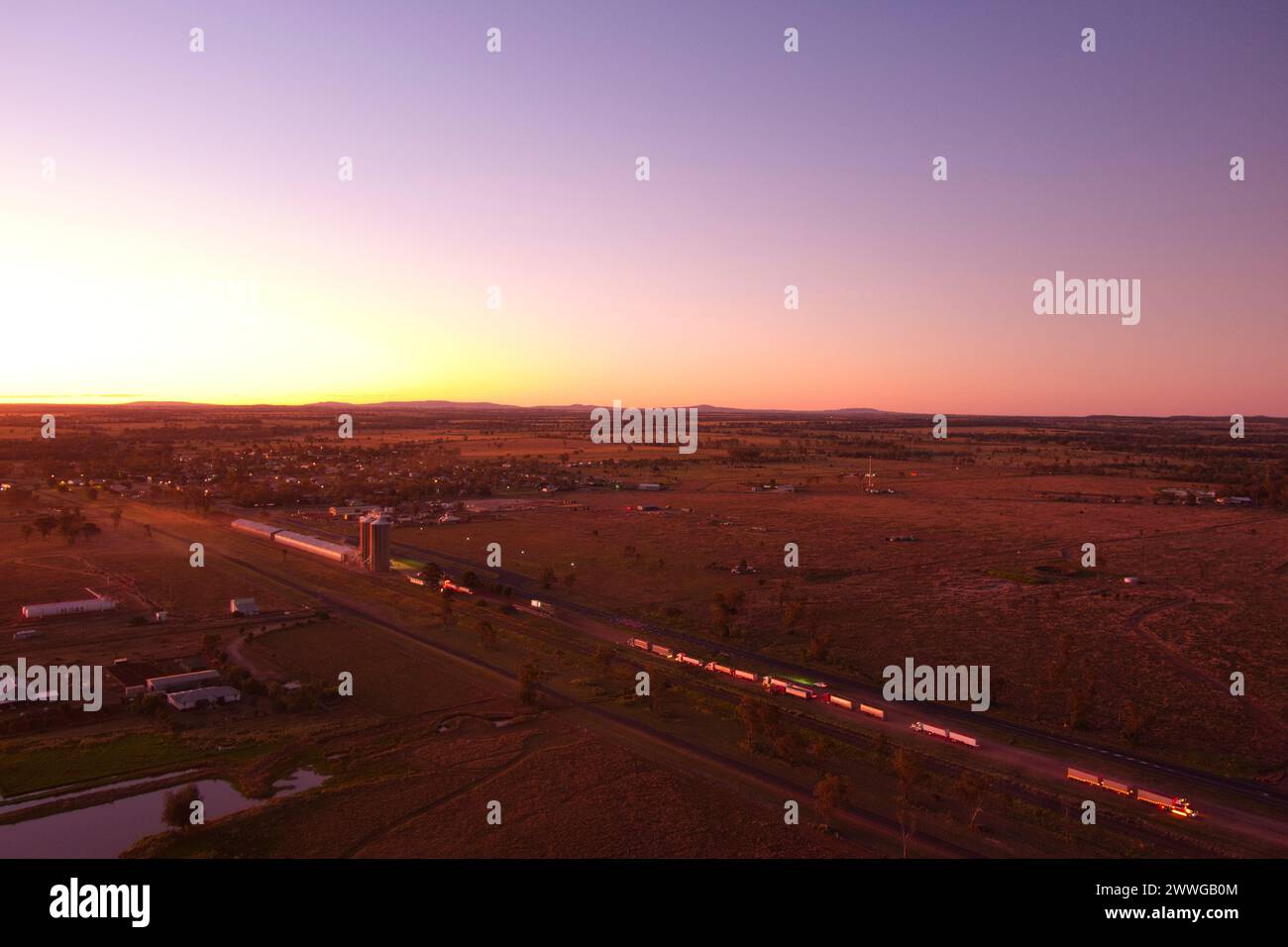 Aérien du coucher du soleil au-dessus de camions livrant du grain de blé au silo de Wallumbilla Queensland Australie Banque D'Images