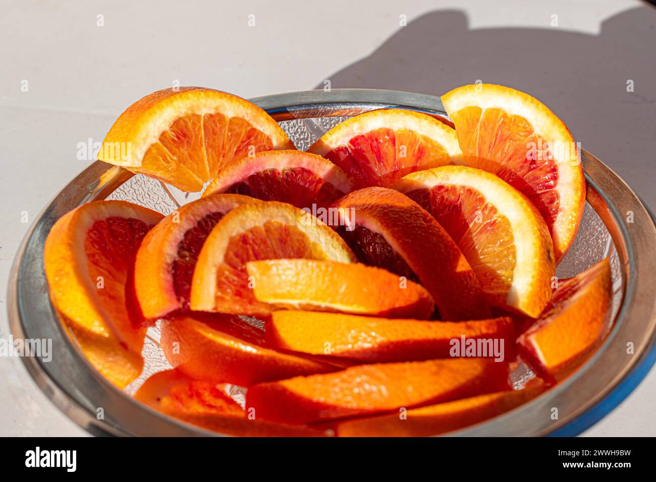 Un bol en verre rempli de tranches d'orange fraîches au soleil Banque D'Images
