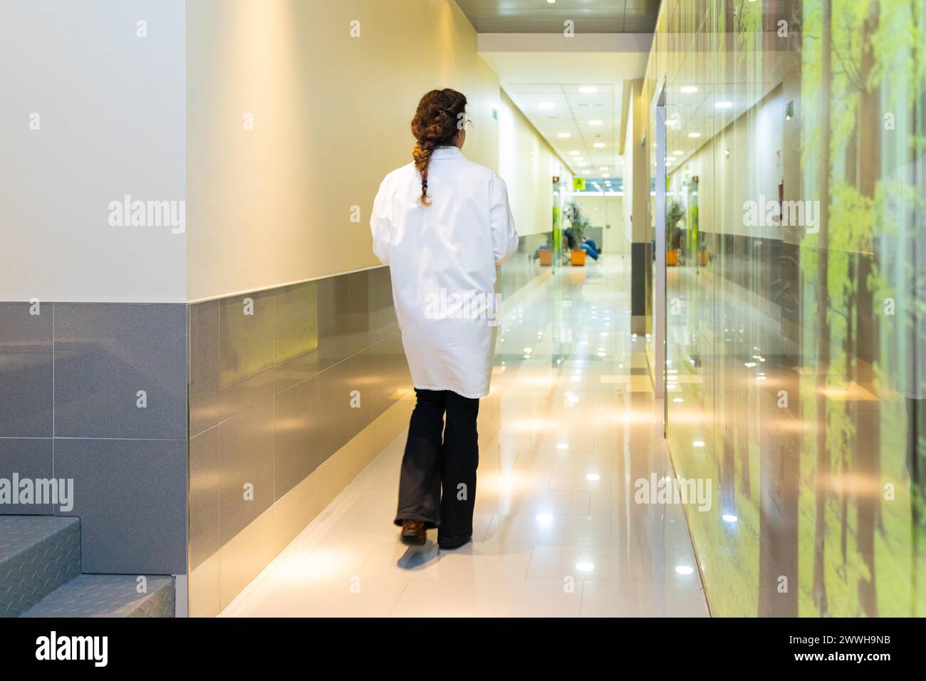 Vue arrière d'une ophtalmologiste marchant le long d'un couloir à la clinique Banque D'Images