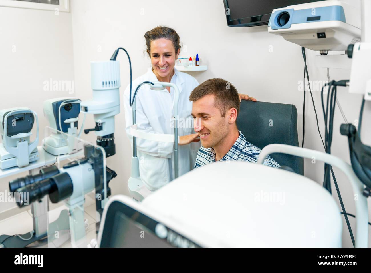 Homme souriant sur un rendez-vous médical avec une ophtalmologiste Banque D'Images