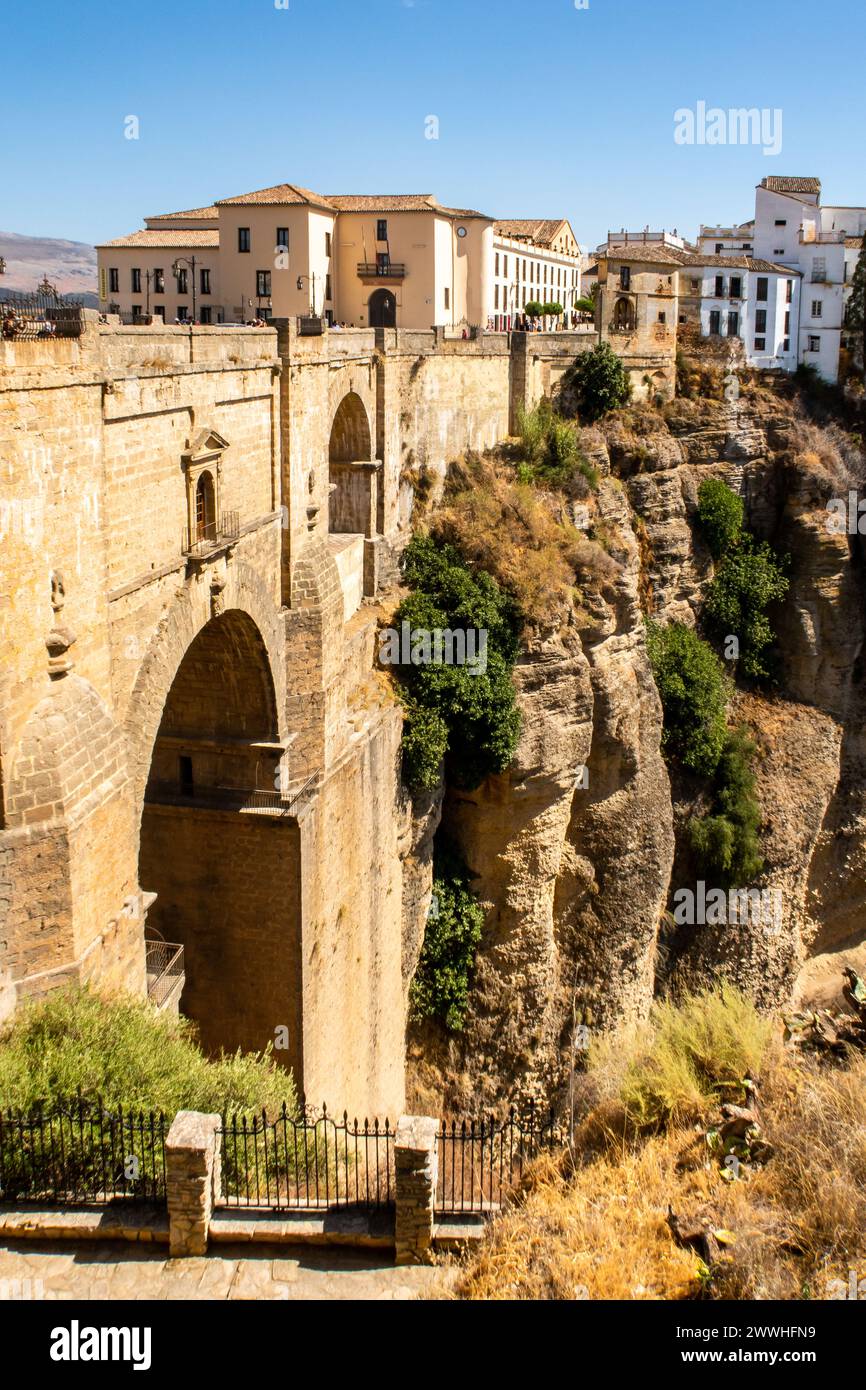 Vue portrait de Ronda et de sa gorge profonde spectaculaire, avec un pont de pierre massif et des arches, construit dans de grandes formations rocheuses, Ronda, Espagne. Banque D'Images