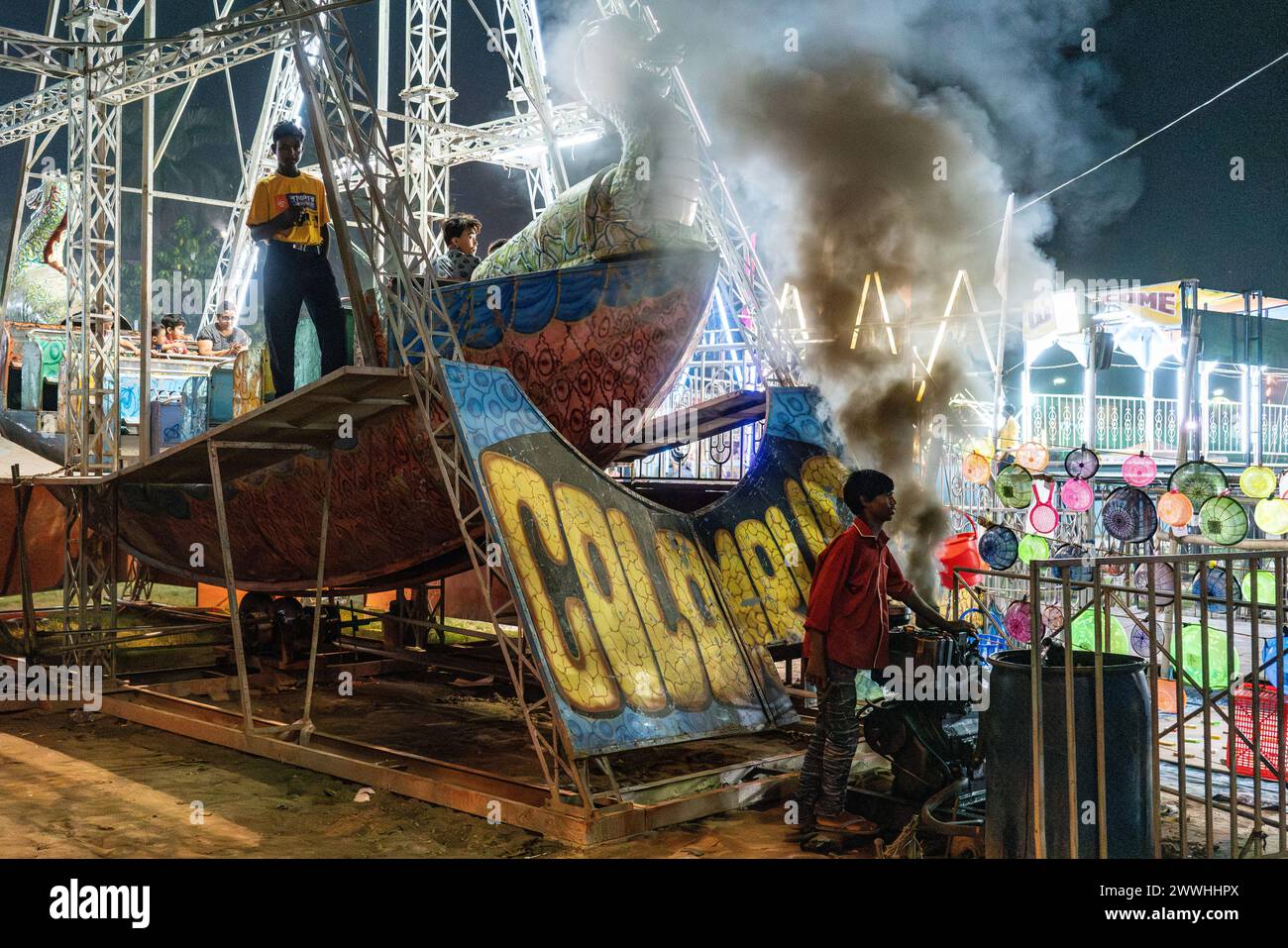 Soufflet de fumée d'un moteur alors que les fêtards attendent le début de la course équitable à Kolkata, en Inde Banque D'Images