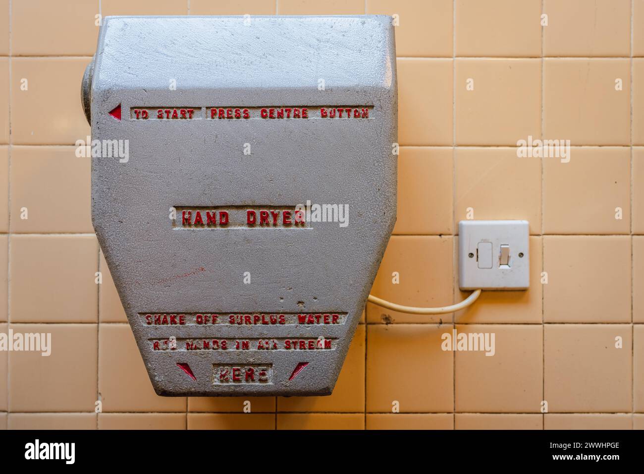 Un très vieux sèche-mains sur un mur carrelé Banque D'Images