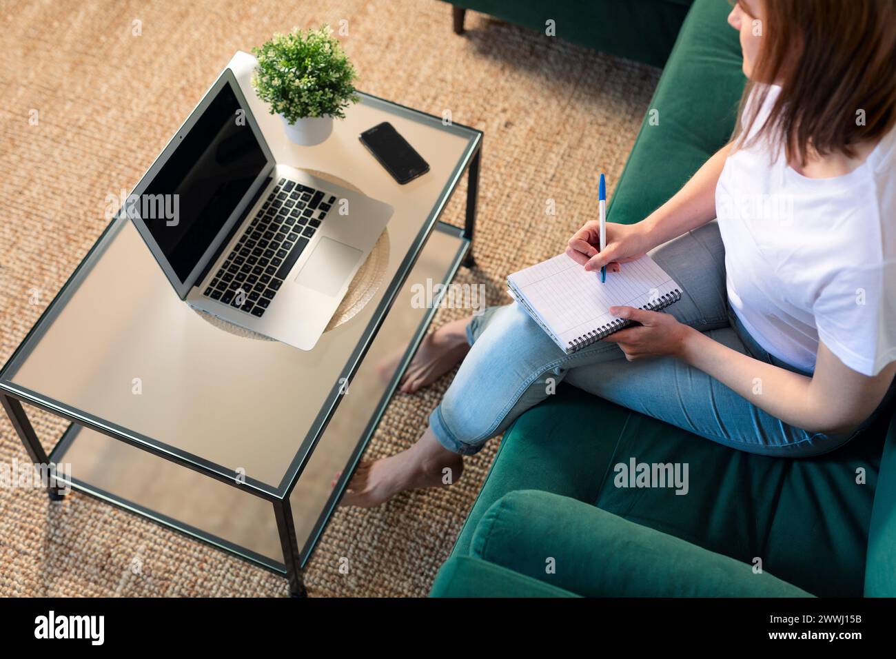 Femme caucasienne travaillant à la maison avec ordinateur portable et ordinateur portable. Écrivez une note sur le livre avec un stylo comme à l'ancienne, mais utilisez Internet sur l'ordinateur Banque D'Images