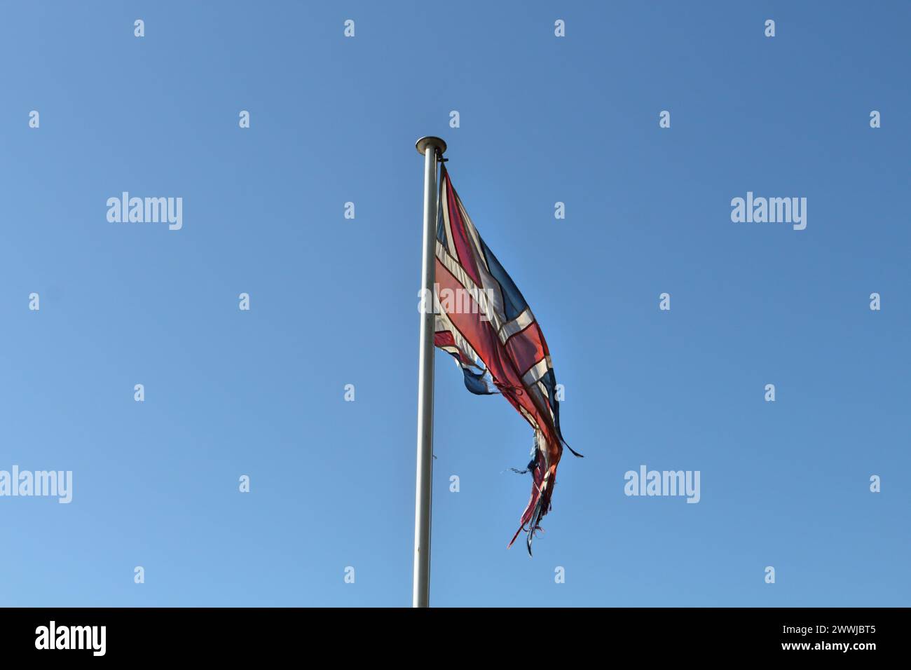 Tatty drapeau Union Jack effiloché volant sur le mât du drapeau Banque D'Images