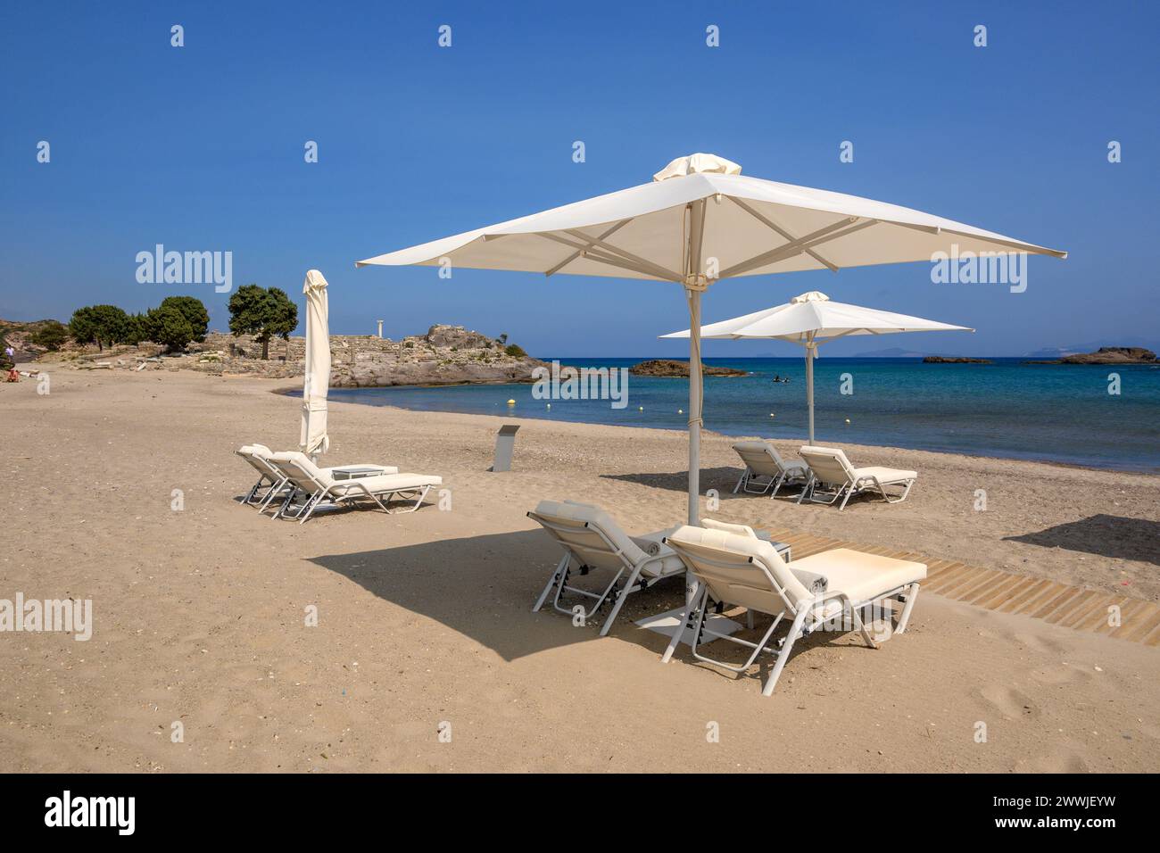 Chaises longues avec parasol sur la plage de sable d'Agios Stefanos. L'île grecque de Kos Banque D'Images