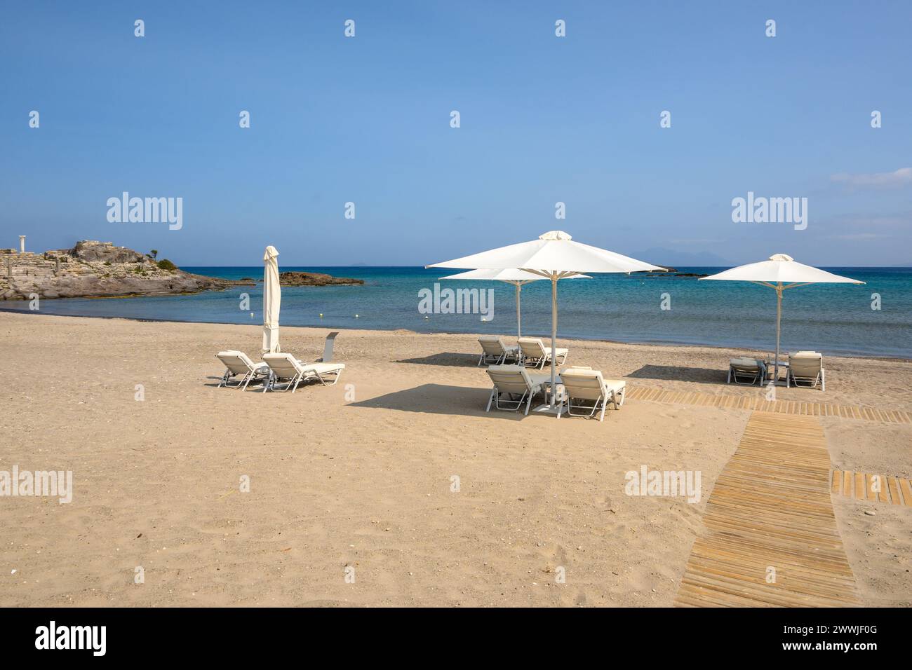 Chaises longues avec parasol sur la plage de sable d'Agios Stefanos. L'île grecque de Kos Banque D'Images