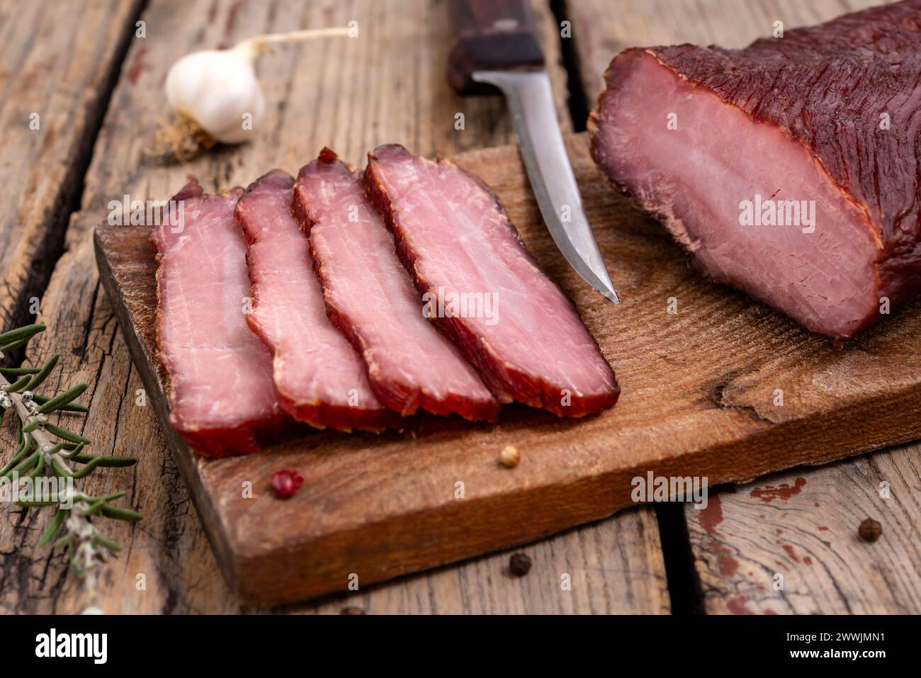 Planche à découper avec de la viande séchée, des épices et un couteau de cuisine sur une table en bois. Mise au point sélective. Banque D'Images