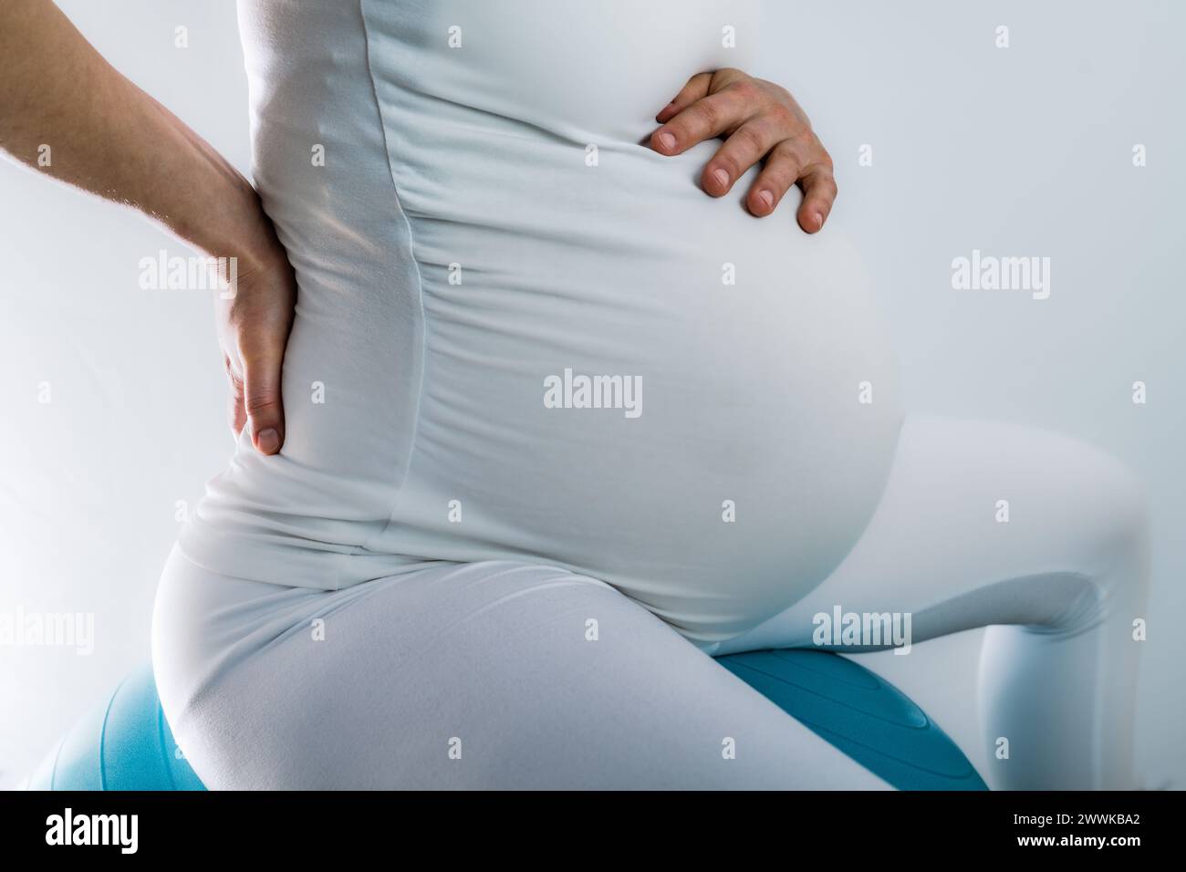 Description : femme enceinte avec bosse de bébé ressent des maux de dos et tient la main sur son dos douloureux. Dernier mois de grossesse - semaine 36. Vue latérale. WHI Banque D'Images