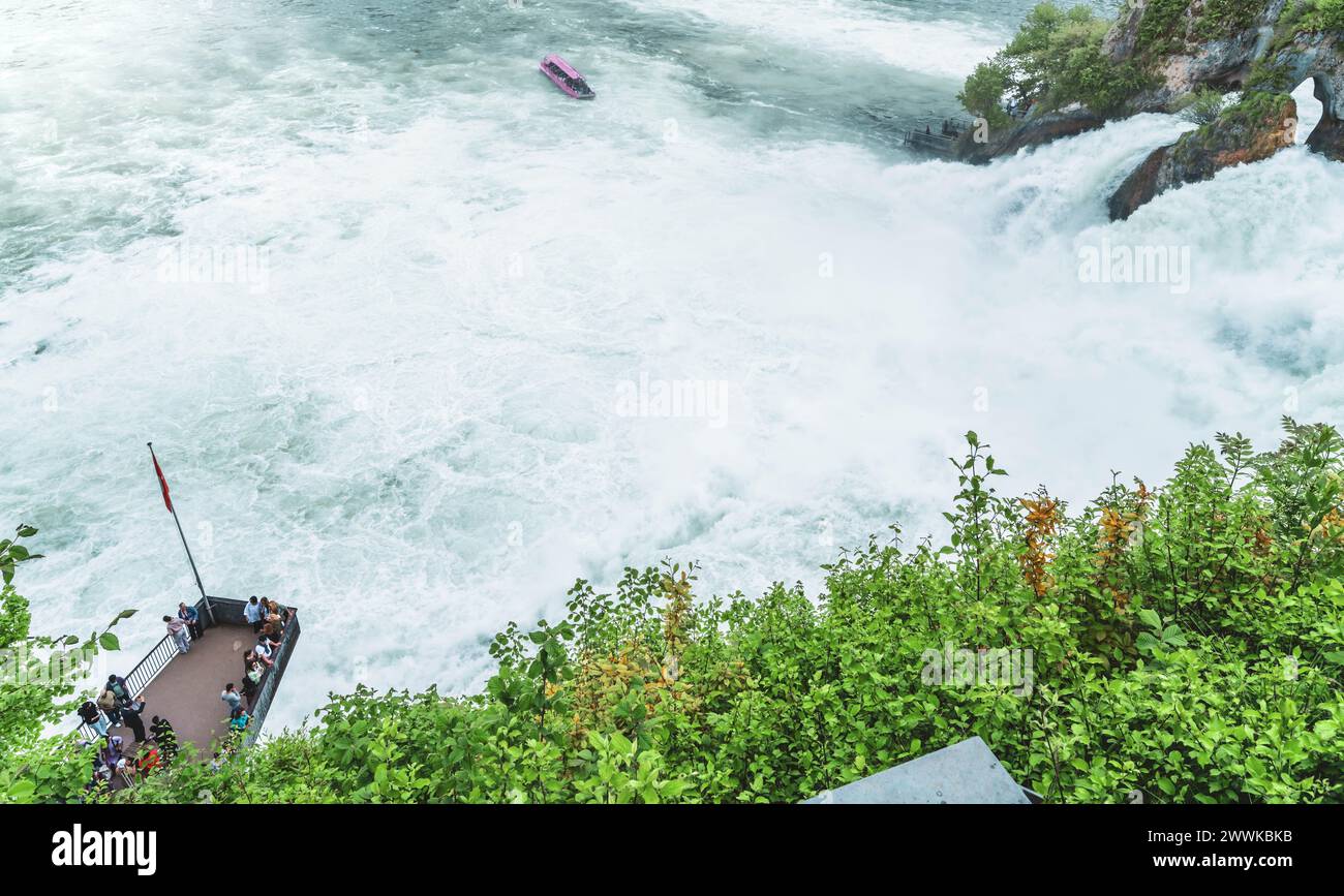Description : les touristes expérimentent les chutes d'eau massives en dessous du château de Laufen aux chutes du Rhin depuis la plate-forme d'observation et le bateau touristique. Chutes du Rhin Banque D'Images
