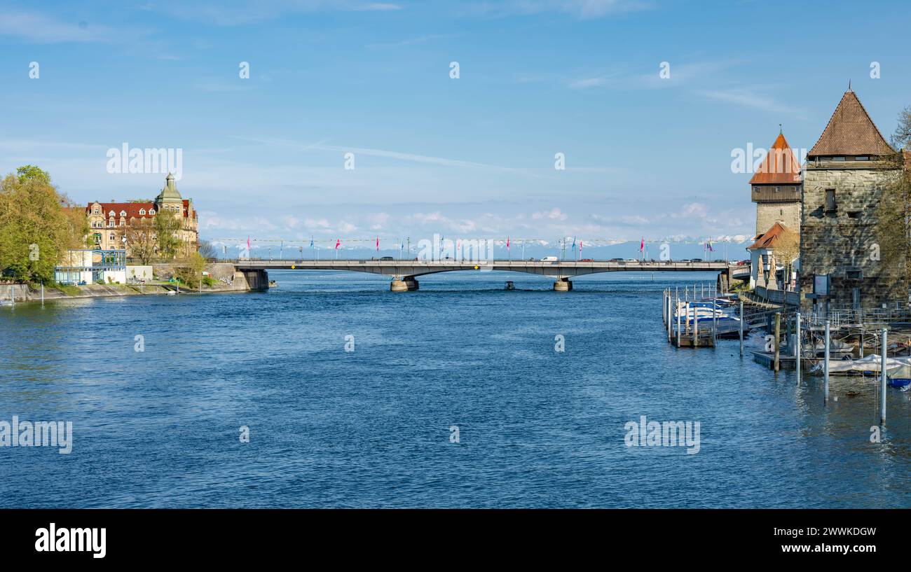 Beschreibung : Fahrzeuge und Fahrradfahrer überqueren die Rheinbrücke an einem sonnigen Frühlingstag mit dem Alpenpanorama im Hintergrund. Konstanz, Bo Banque D'Images