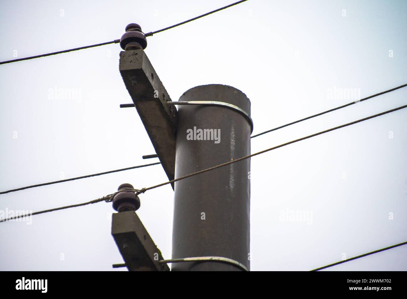 Au milieu du paysage urbain, des colonnes et des câbles électriques tissent un réseau d’énergie, reliant les espaces urbains à l’impulsion invisible du pouvoir et de la vie moderne Banque D'Images