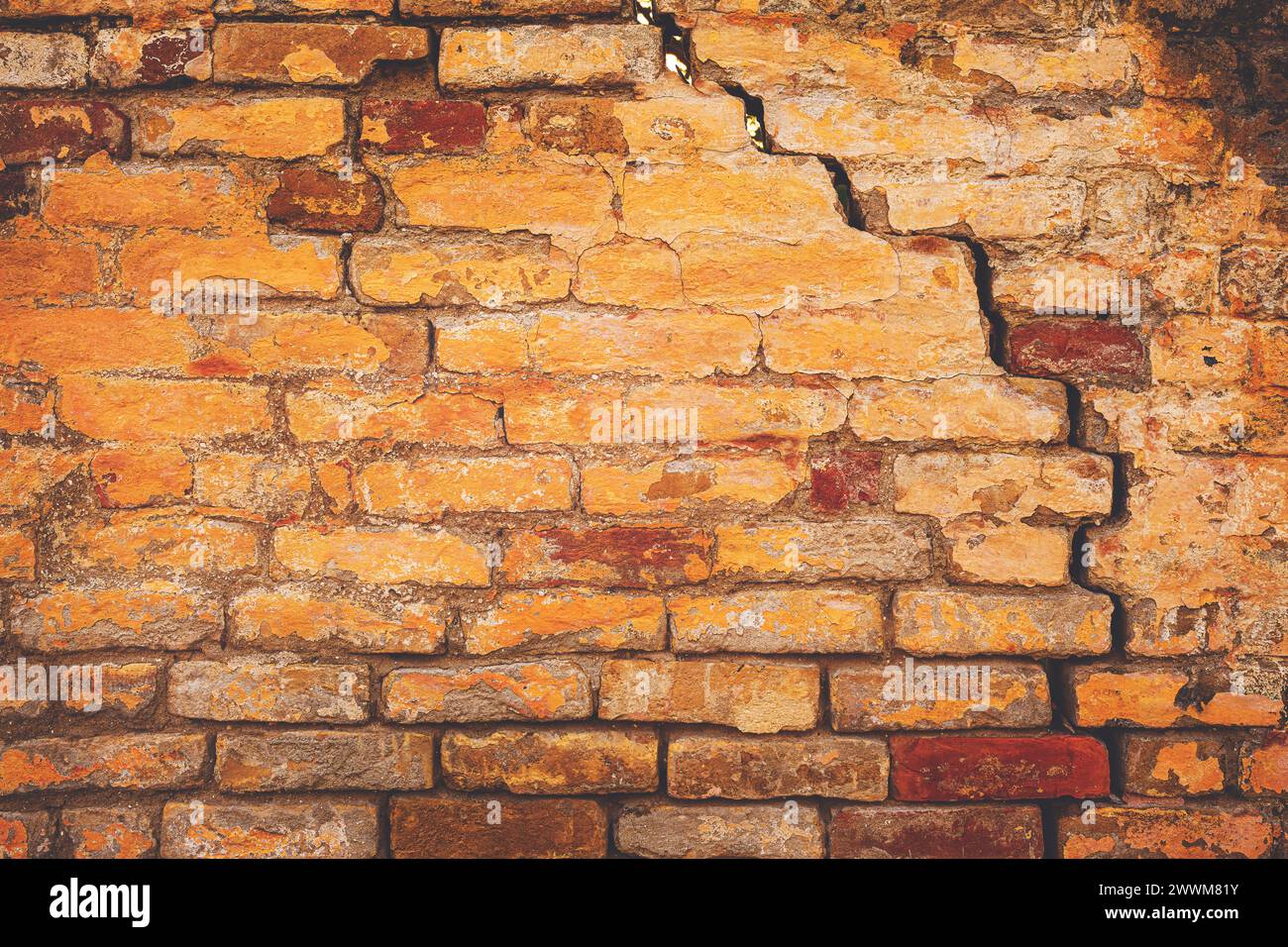 Ancienne structure de mur de briques fissurée endommagée, en raison de la défaillance de la fondation structurelle et de la détérioration des matériaux de construction, comme fond urbain Banque D'Images