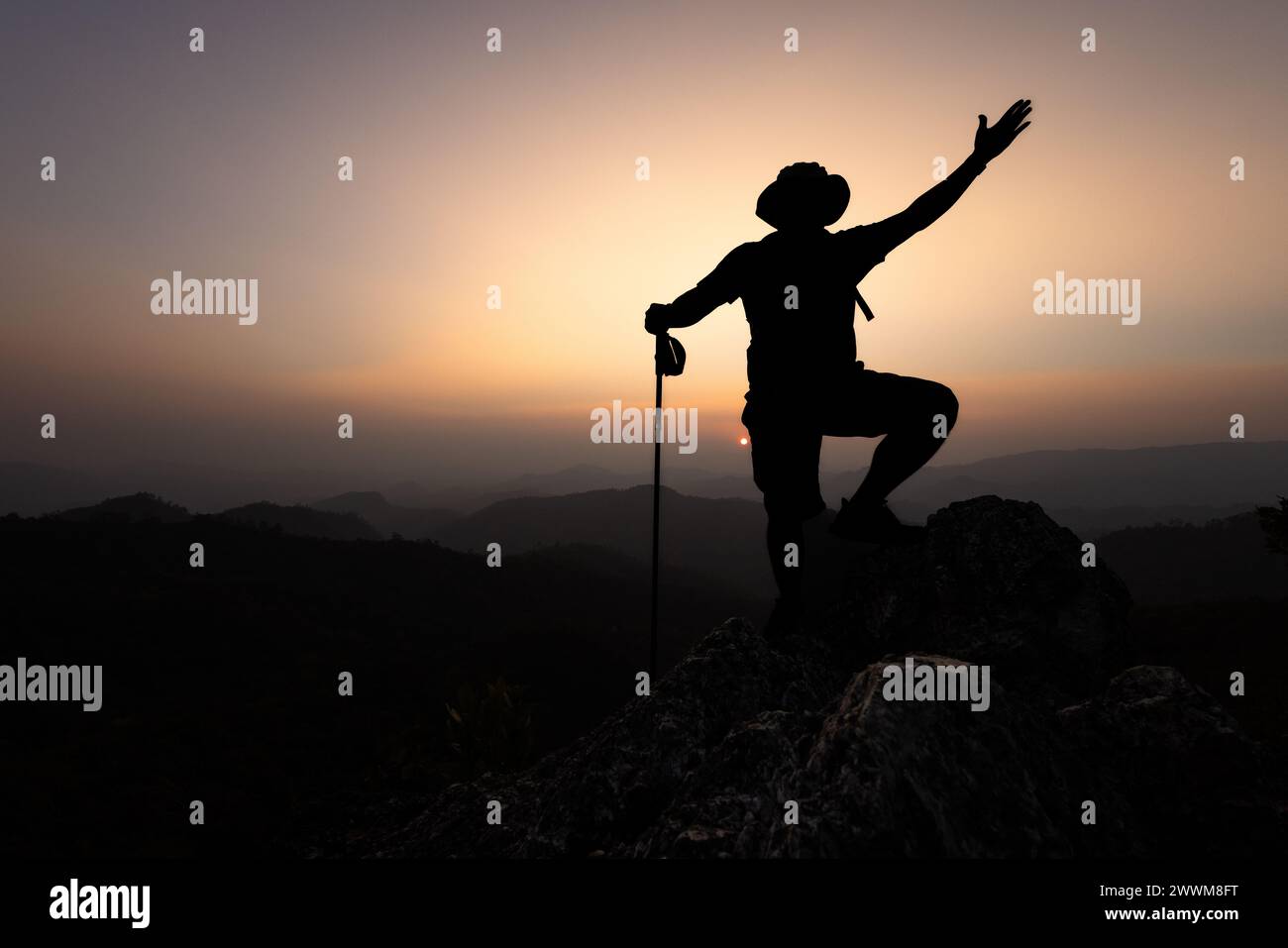 Grimpeur succès, silhouette réalisations réussi ARM Up Man est au sommet de la colline célébrant le succès avec le lever du soleil. Banque D'Images
