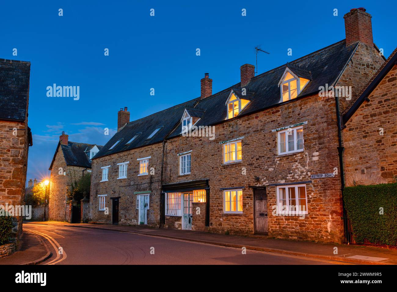 Des cottages en pierre s'illuminèrent au crépuscule. Kings Sutton, Northamptonshire, Angleterre Banque D'Images