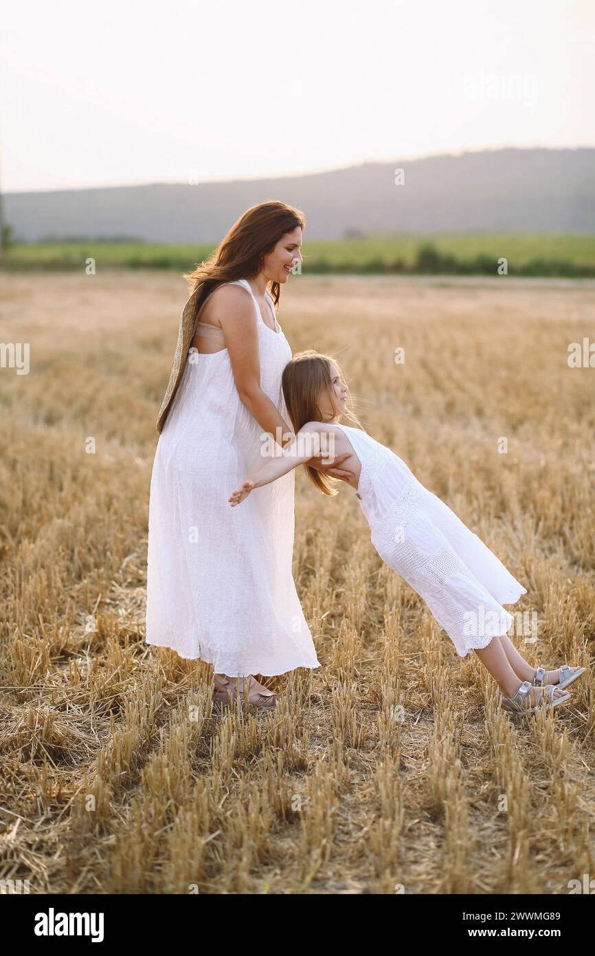 Heureuse mère et fille dans des robes d'été s'amusant sur le terrain Banque D'Images