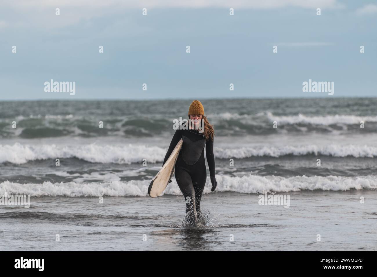 Femme marchant sur la plage avec planche de surf hiver islande Banque D'Images
